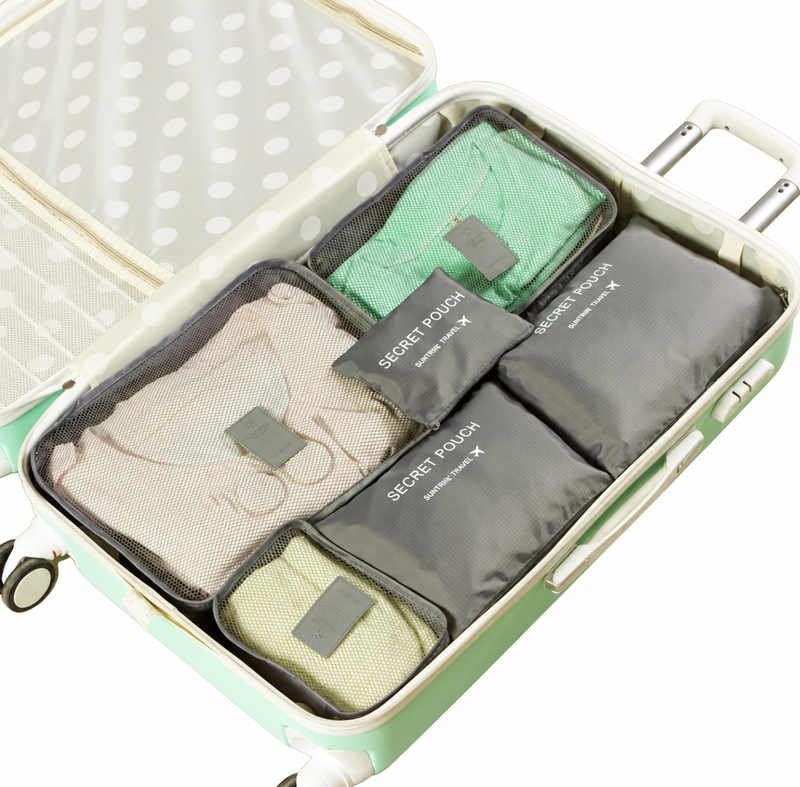 Grey six-piece packing organizers shown in an open suitcase against a white background; suitcase and contents are styling props.